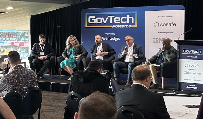 Mark Kirkpatrick sitting on stage with panelists at conference